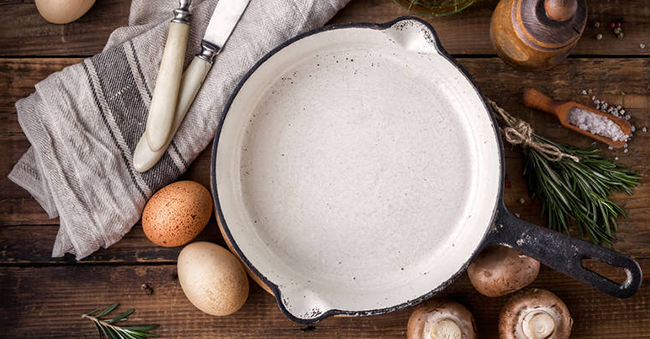 Ingredients for cooking and cast iron skillet on an old wooden table. Food background with copy space. Top view